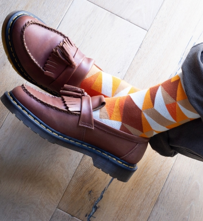 Orange and brown geometric socks worn with leather loafers