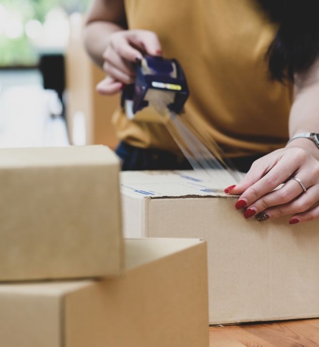 Team member sealing cartons for multi-destination shipping