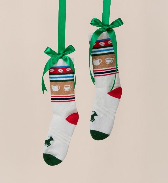 Two custom holiday socks hanging from green ribbons
