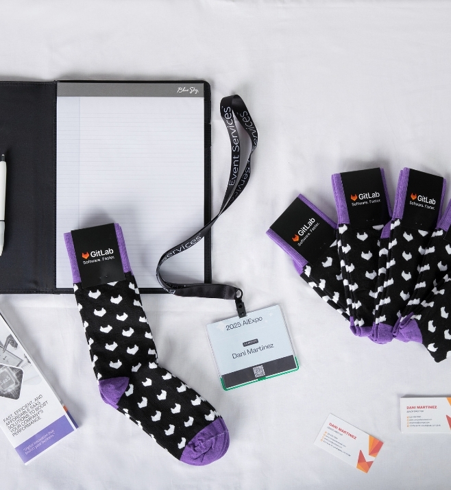 GitLab conference socks displayed beside a badge and notebook