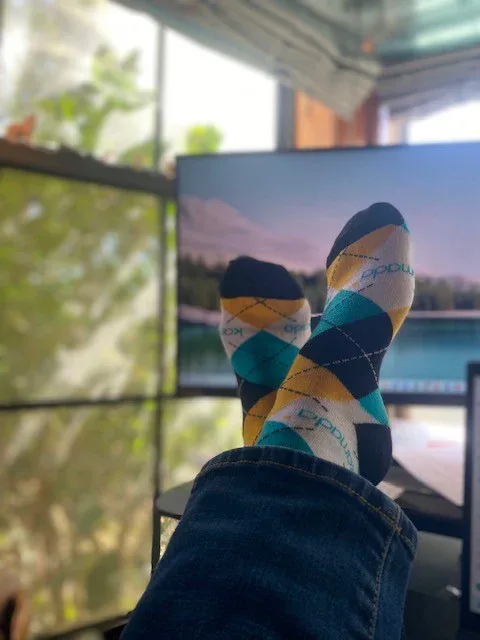 Blue, yellow, and white argyle custom socks worn at a desk